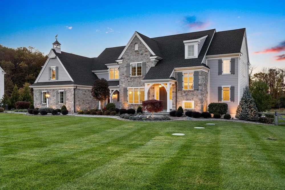 Large stone and siding home at dusk with manicured lawn